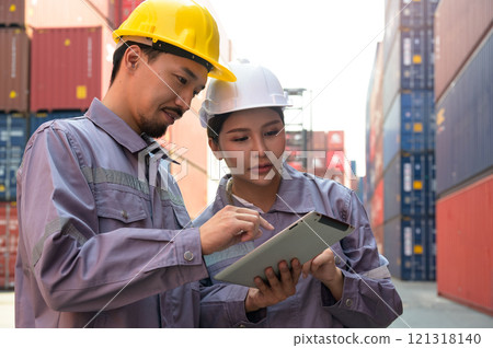 Two engineer technician working together on digital tablet for loading containers control in import and export area at cargo shipping yard 121318140