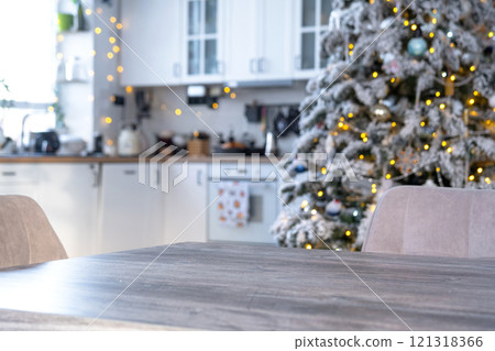 Grey Wooden empty table to demonstrate product with space for text with upholstered chairs in white kitchen, modern interior with Christmas tree and fairy lights. New Year, Christmas mood, cozy home. 121318366