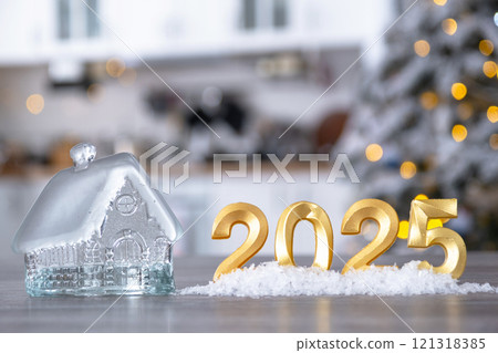 Golden number 2025, key and tiny home on background of cozy white kitchen with Christmas tree and Christmas decor with garland lights. Housing, interior, renovation, mortgage, rent in New Year Golden number 2025, key and tiny home on background of cozy white kitchen with Christmas tree and Christmas decor with garland lights. Housing, interior, renovation, mortgage, rent in New Year 121318385
