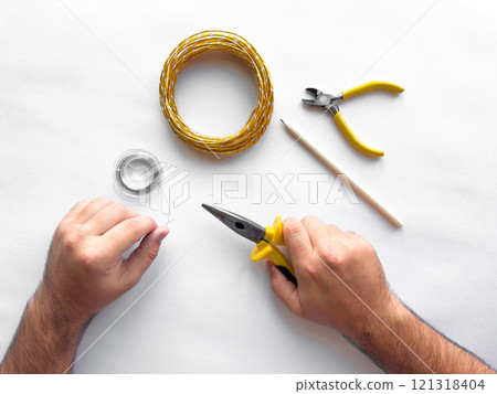 Hands crafting wire jewelry with tools on white background Hands crafting wire jewelry with tools on white background 121318404