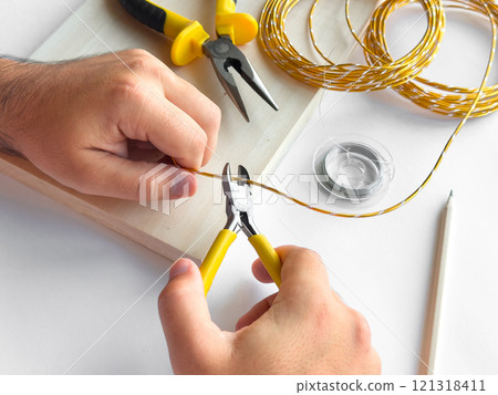 Hands crafting jewelry with wire cutters and twisting tools Hands crafting jewelry with wire cutters and twisting tools 121318411