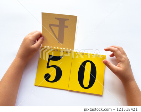 Childs hands flip through yellow pages with numbers. Displaying number 50 on white background 121318421