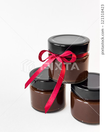 Luxurious chocolate spread jars with red ribbon tied for gift giving elegance Luxurious chocolate spread jars with red ribbon tied for gift giving elegance 121318423