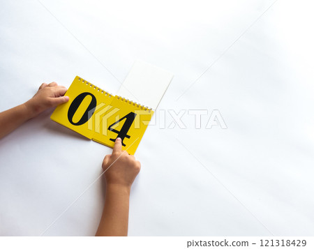 Hands flipping calendar page to number four on yellow notebook Hands flipping calendar page to number four on yellow notebook 121318429
