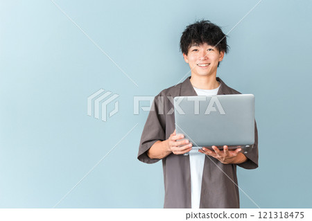 A young man of the digital native generation holding a personal computer 121318475