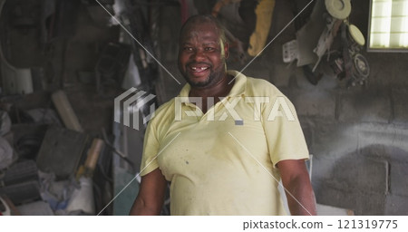 Portrait of a happy African handyman in a township workshop, looking at camera and smiling, slow mot 121319775