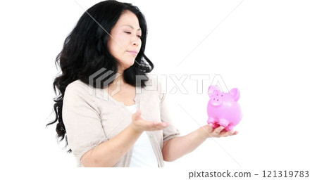 Thoughtful Asian woman holding and looking a piggy bank on white screen 121319783