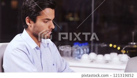 Attentive businessman working on laptop in office at night 121319852