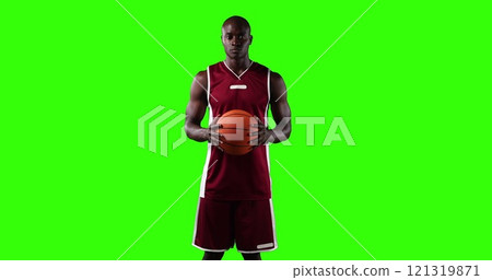 Portrait of confident male African American basketball player wearing red sports clothes, holding an 121319871