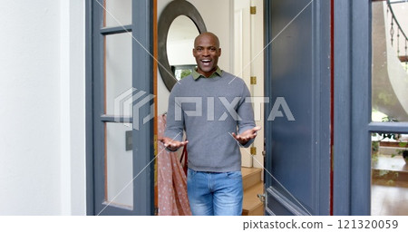 Happy african american man welcoming at his front door Happy african american man welcoming at his front door 121320059