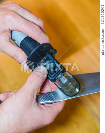 Man sharpening a knife with a handheld sharpener. High quality photo 121320201