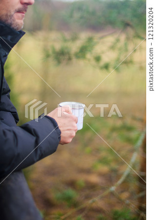 Man Holding a white Mug Outdoors in Nature with a Peaceful Background. High quality photo 121320204