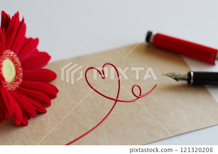 Red gerbera and brown message card, image of writing with a red fountain pen, red heart wire 121320208