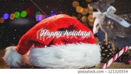 Image of happy holidays text over snow falling with christmas santa claus hat and decorations Image of happy holidays text over snow falling with christmas santa claus hat and decorations 121320554