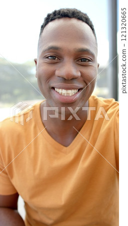 Vertical image of portrait of happy african american man having image call Vertical image of portrait of happy african american man having image call 121320665