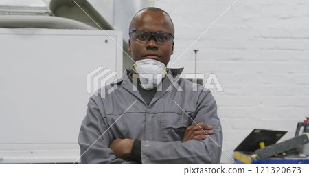 Portrait of an African American male car mechanic working in a township workshop, crossing his arms Portrait of an African American male car mechanic working in a township workshop, crossing his arms 121320673