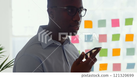 Side view of young black businessman talking on mobile phone in a modern office 121320699