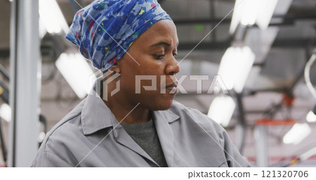 African American female car mechanic working in a township workshop, painting a body of a car in slo African American female car mechanic working in a township workshop, painting a body of a car in slo 121320706