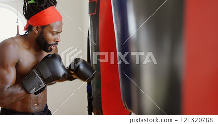 Side view of male boxer practicing boxing in fitness studio Side view of male boxer practicing boxing in fitness studio 121320788