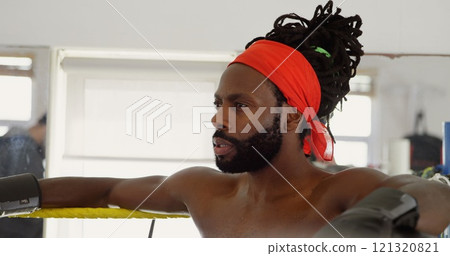 Male boxer relaxing in boxing ring at fitness studio 121320821