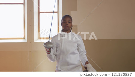 Portrait of a focused biracial female fencer athlete during a fencing training in a gym, walking wea Portrait of a focused biracial female fencer athlete during a fencing training in a gym, walking wea 121320827