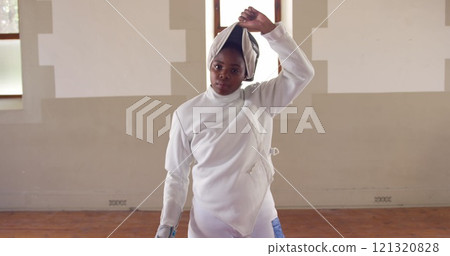 Portrait of a happy biracial female fencer athlete during a fencing training in a gym, walking weari Portrait of a happy biracial female fencer athlete during a fencing training in a gym, walking weari 121320828
