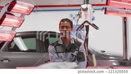 Portrait of an African American male car mechanic working in a township workshop, crossing his arms 121320850
