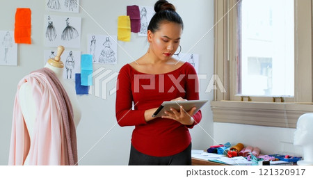 Fashion designer using digital tablet while working on dressmakers model at design studio 4k 121320917