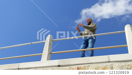 Low angle view of man taking photo with mobile phone near railing 121320919
