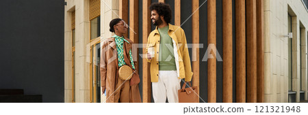 Two colleagues standing outdoors, having an animated conversation while holding coffee cups, one holding a briefcase. Professional attire suggests engaging in a business discussion Two colleagues standing outdoors, having an animated conversation while holding coffee cups, one holding a briefcase. Professional attire suggests engaging in a business discussion 121321948