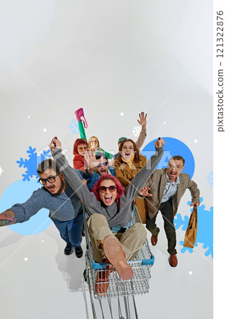 Shoppers celebrating discounts by riding shopping cart, expressing happiness and excitement about winter sales 121322876