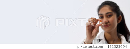 Banner. Portrait of of young attractive woman demonstrate one pill against white studio background with negative space to insert text. 121323694