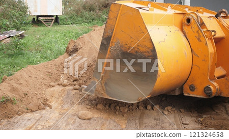 A heavy machinery excavator bucket is currently engaged in digging soil specifically for construction purposes A heavy machinery excavator bucket is currently engaged in digging soil specifically for construction purposes 121324658