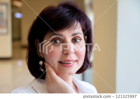 Portrait of a middle aged woman with white earrings 121325997