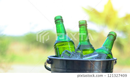 Green beer bottle rest in a bucket of ice, symbolizing refreshment and relaxation, perfect for unwinding during social gatherings or celebrating special moments. Green beer bottle rest in a bucket of ice, symbolizing refreshment and relaxation, perfect for unwinding during social gatherings or celebrating special moments. 121327409
