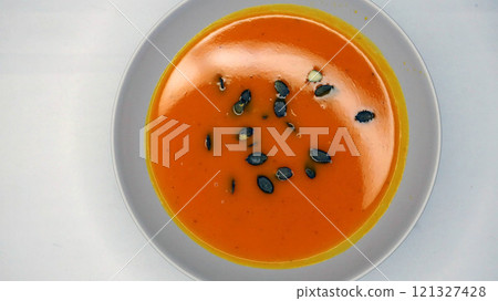 Creamy orange pumpkin soup with seeds served on a table. Creamy orange pumpkin soup with seeds served on a table. 121327428