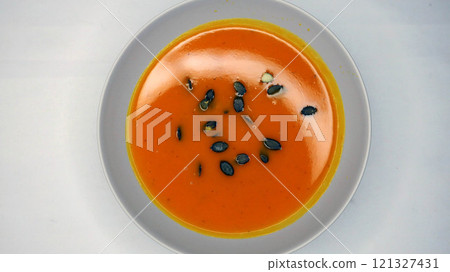 Creamy orange pumpkin soup with seeds served on a table. 121327431