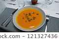 Creamy orange pumpkin soup with seeds served on a table. 121327436