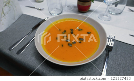 Creamy orange pumpkin soup with seeds served on a table. 121327453