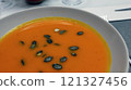 Creamy orange pumpkin soup with seeds served on a table. 121327456