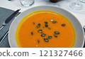 Creamy orange pumpkin soup with seeds served on a table. 121327466