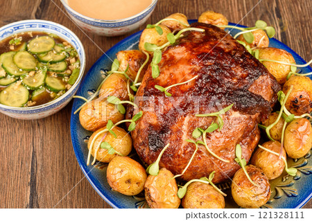 Baked pork ham with glaze and baby potatoes, garnished with microgreens. 121328111