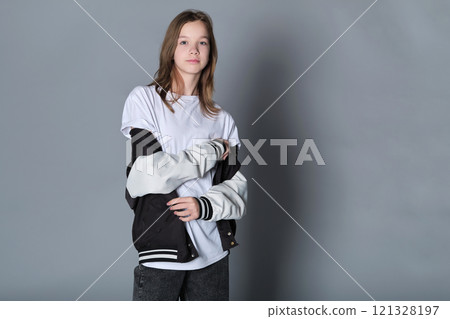 A girl stands in a relaxed pose with her jacket over her shoulders, gazing down. This image embodies the calm confidence of adolescence and the journey toward self-discovery. 121328197