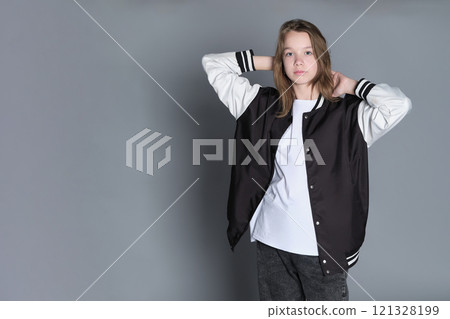 A teenage girl in profile with a varsity jacket resting on her shoulder, giving off a relaxed vibe. Her natural expression highlights youthful energy and individuality. 121328199