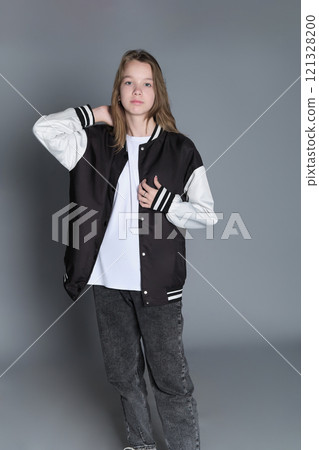 A teenage girl in profile with a varsity jacket resting on her shoulder, giving off a relaxed vibe. Her natural expression highlights youthful energy and individuality. A teenage girl in profile with a varsity jacket resting on her shoulder, giving off a relaxed vibe. Her natural expression highlights youthful energy and individuality. 121328200