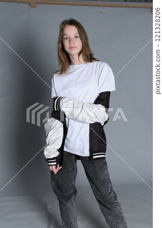 A girl stands in a comfortable, stylish outfit, her gaze directed forward. This portrait highlights the spirit of individuality and the laid-back attitude of today s young generation. 121328206