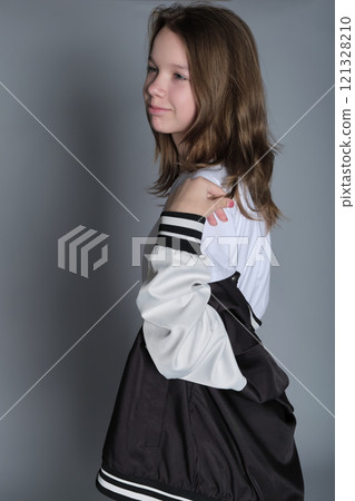 The young girl stands with a confident expression, wearing a casual yet stylish outfit. Her look embodies the balance of youthful innocence and emerging self-awareness common in adolescence. The young girl stands with a confident expression, wearing a casual yet stylish outfit. Her look embodies the balance of youthful innocence and emerging self-awareness common in adolescence. 121328210