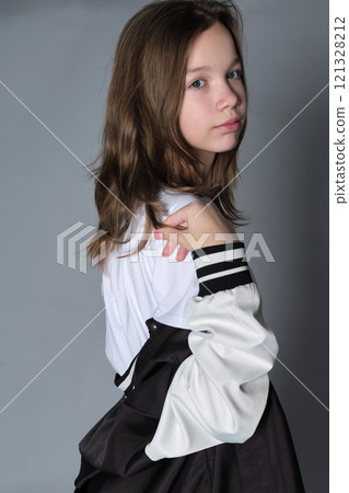 A girl turns slightly, looking thoughtfully to the side, her jacket resting on her shoulder. This portrait expresses the blend of innocence and emerging maturity seen in adolescence. A girl turns slightly, looking thoughtfully to the side, her jacket resting on her shoulder. This portrait expresses the blend of innocence and emerging maturity seen in adolescence. 121328212