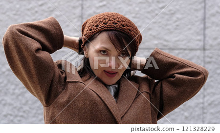 A woman adjusts her outfit thoughtfully, exuding confidence and comfort in the cool weather. 121328229