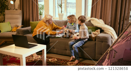 Grandmother guiding girl to check dog's ear with medical tools, teaching care for others, boy watches, learning about responsibility and health basics. Grandmother guiding girl to check dog's ear with medical tools, teaching care for others, boy watches, learning about responsibility and health basics. 121328658